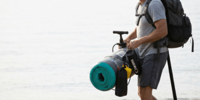 person carrying rolled inflatable paddle board package with 20260303 075020